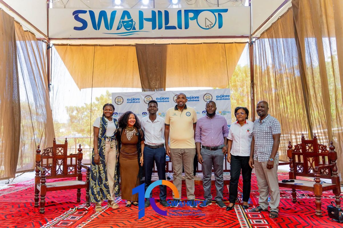 Participants posing for a group photograph beneath the Swahilipot sign, with an Explore Mombasa backdrop